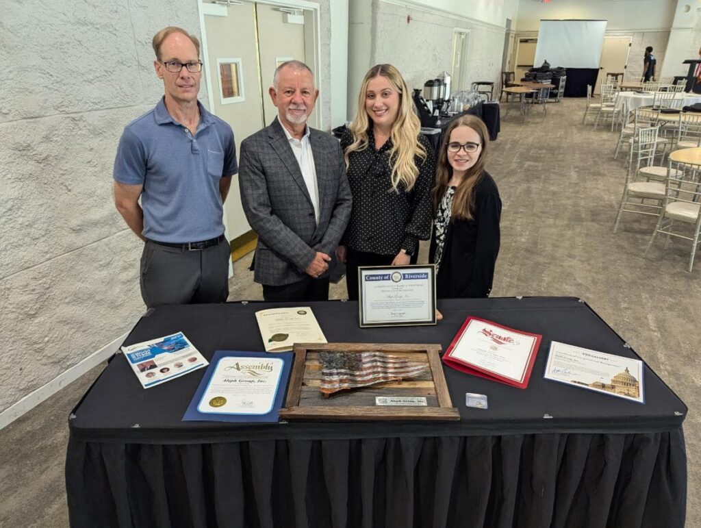 Jales and staff posing in front of a table with all the awards received during for Exporter of the Year.